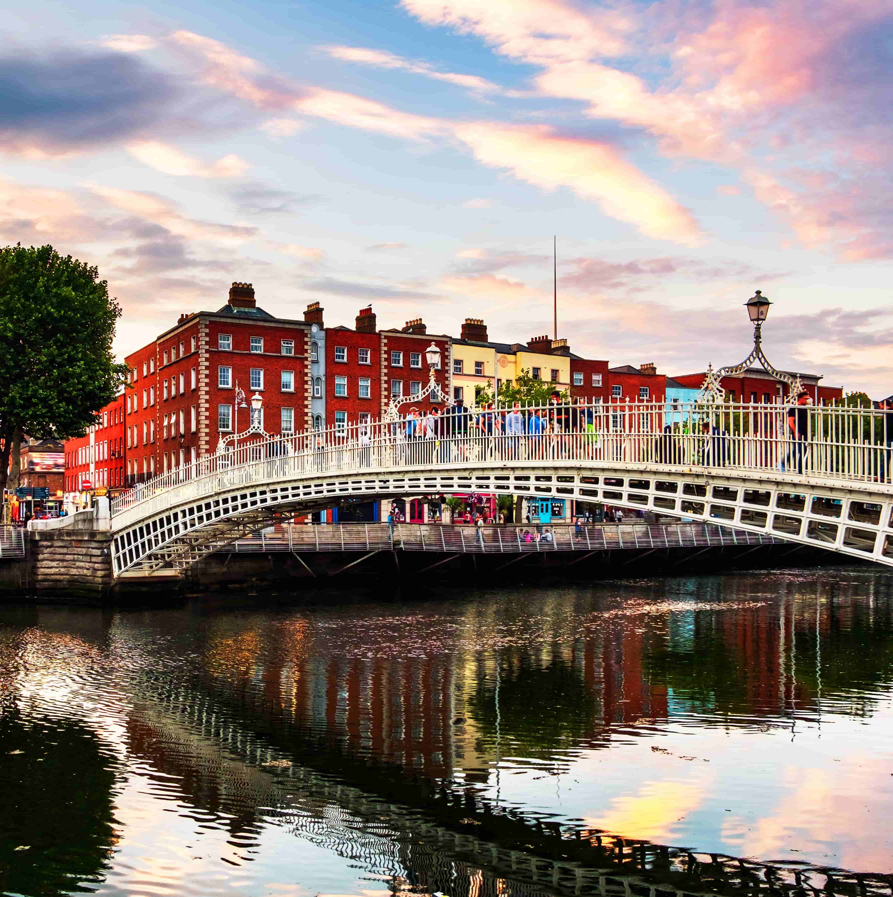 the setting sun paints a vibrant scene of a large bridge providing passage for dozens of people in dublin