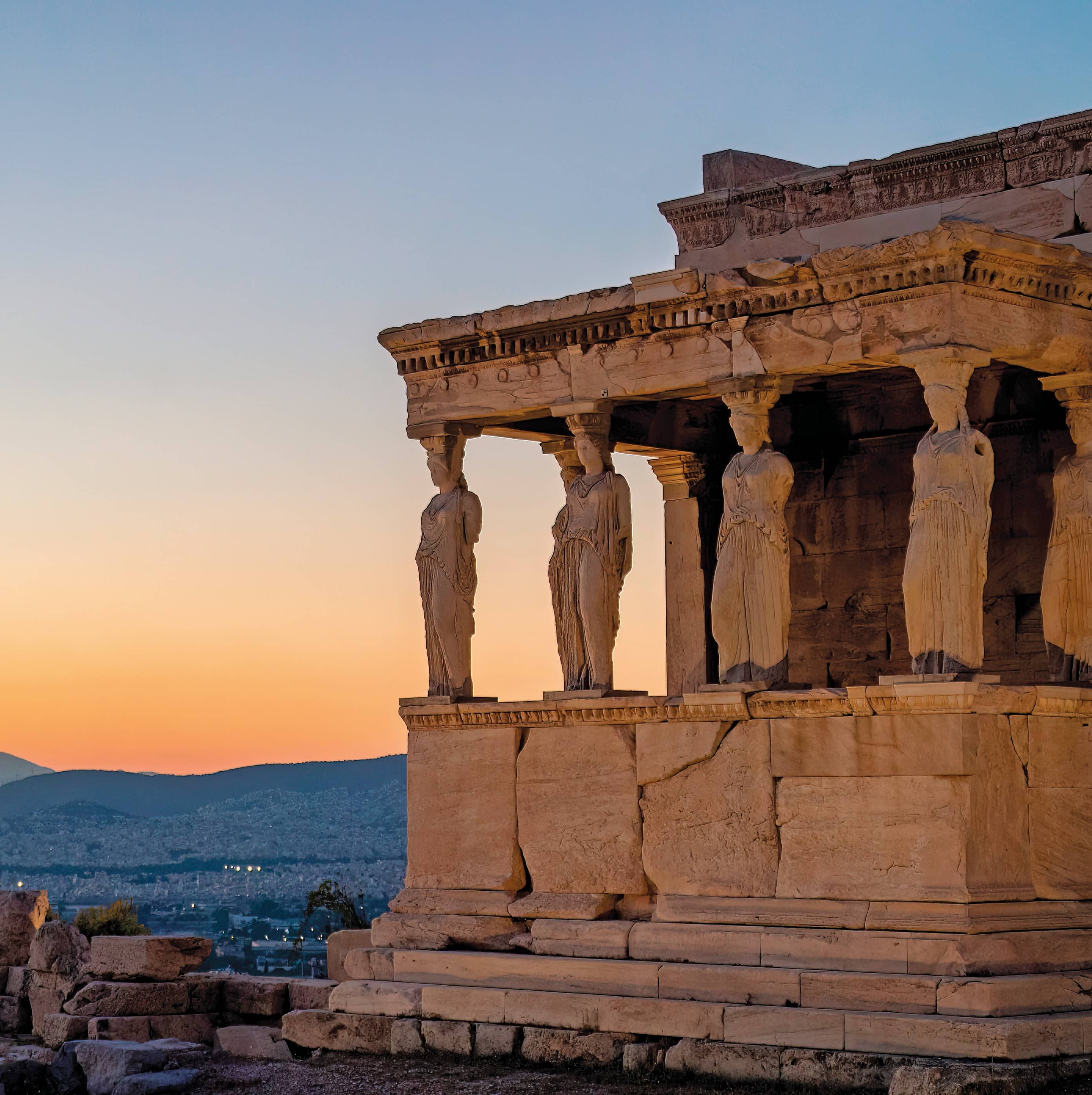 A photo of ancient greek achitecture that portrays 5 collumns in th shape of women in robes holding up an old cieling.  