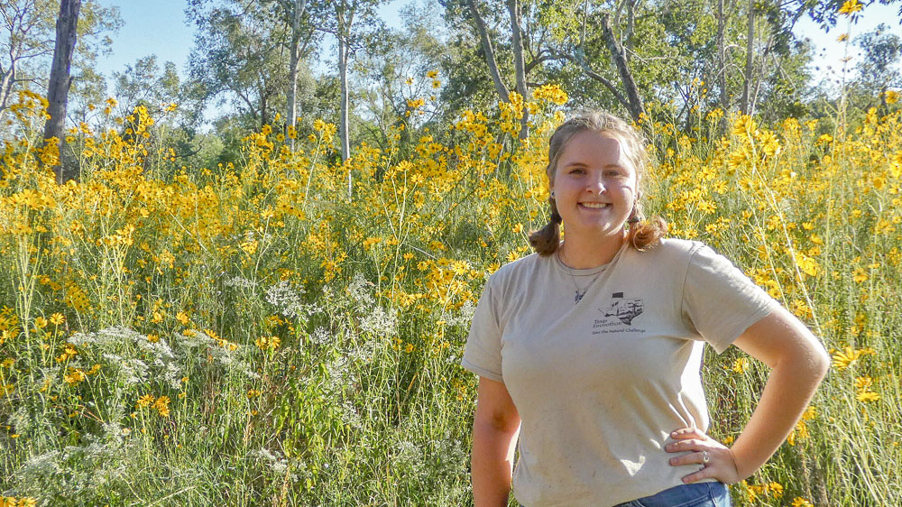 Loralei Miller A person stands in front of a field of tall yellow flowers.