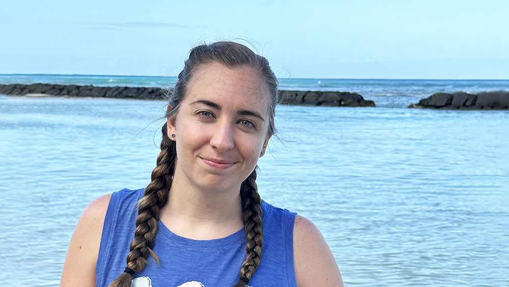 Kylie Perkins Kylie is smiling at the camera against an ocean backdrop, with jetties extending into the water
