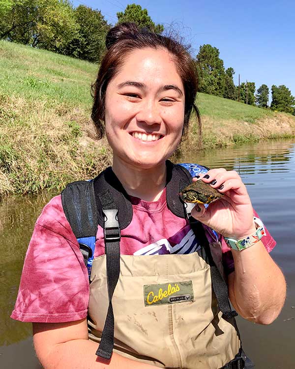 Robyn Gray Robyn is holding a small aquatic turtle as she smiles into the camera.