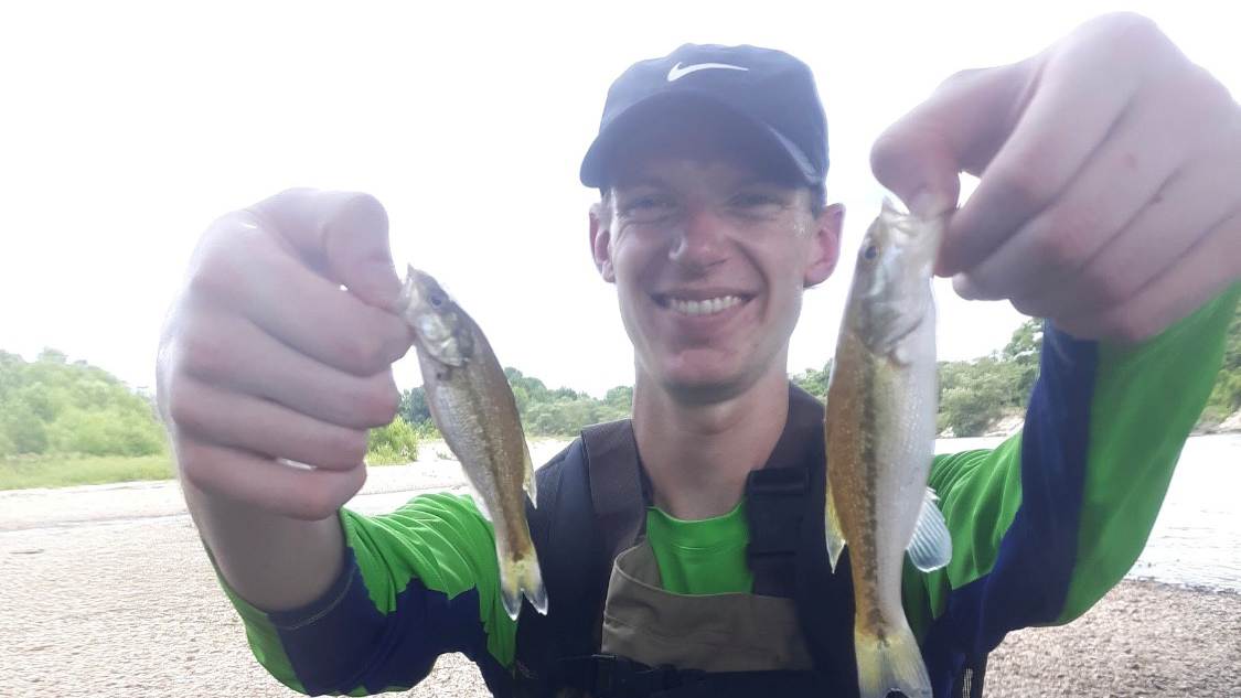 Aaron Krolow Aaron is holding two small fish up to the camera.