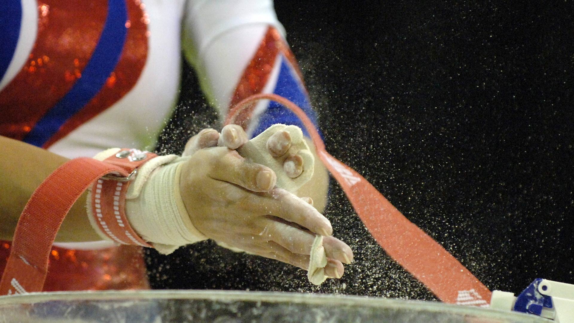 A gymnast chalking her hands